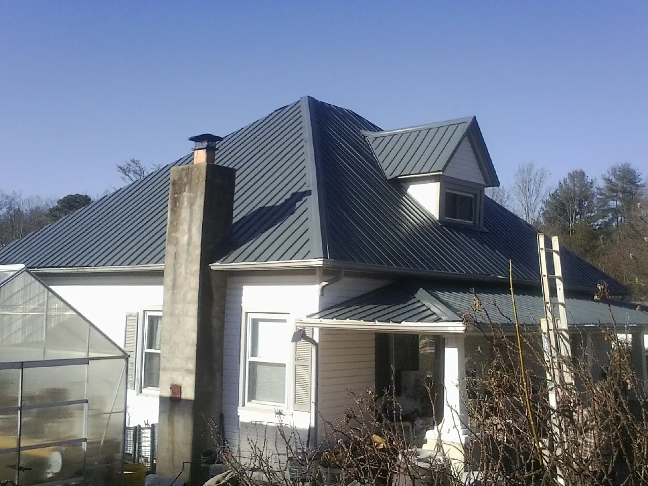 Dark blue standing seam metal roof on a white farmhouse with dormer — Slate & Tile Roof Repair by Roofing Brothers in Swarthmore