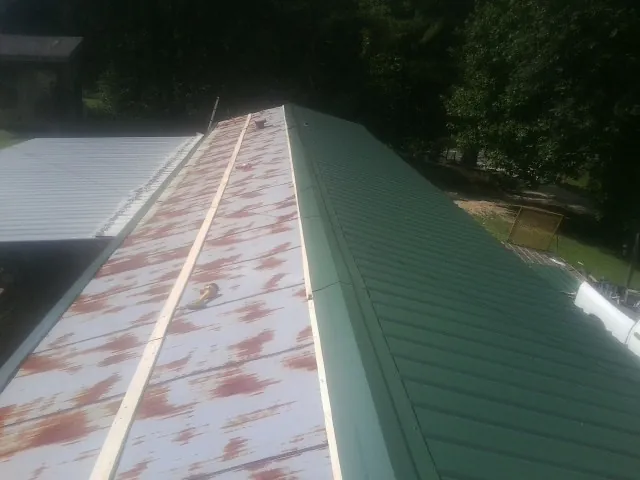Old rusted panels beside newly installed green metal roofing — Wind Damage Roof Repair by Roofing Brothers in Swarthmore
