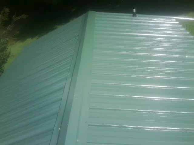 New green metal panels meeting at the ridge of a roof — Flat Roof Repair work by our crew in Swarthmore