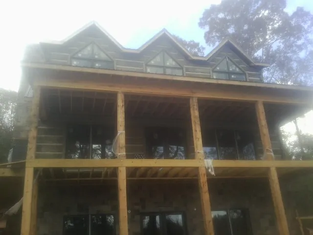 Dormers and porch framing on a large log home under construction — Roof Coating work by our crew in Swarthmore