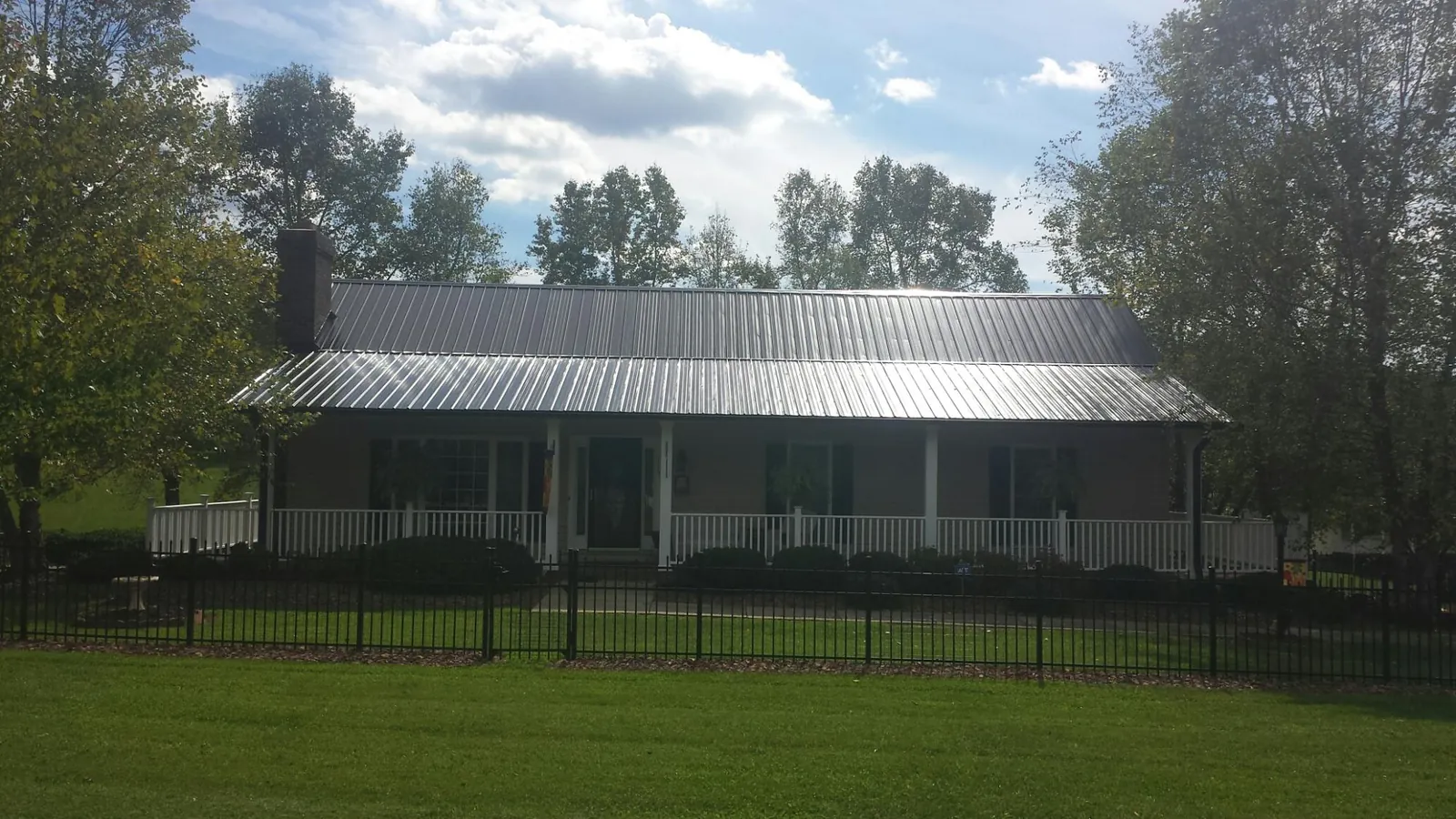 Gray metal roof on a brick ranch with a full width front porch — Gutter Guard Installation work by our crew in Swarthmore