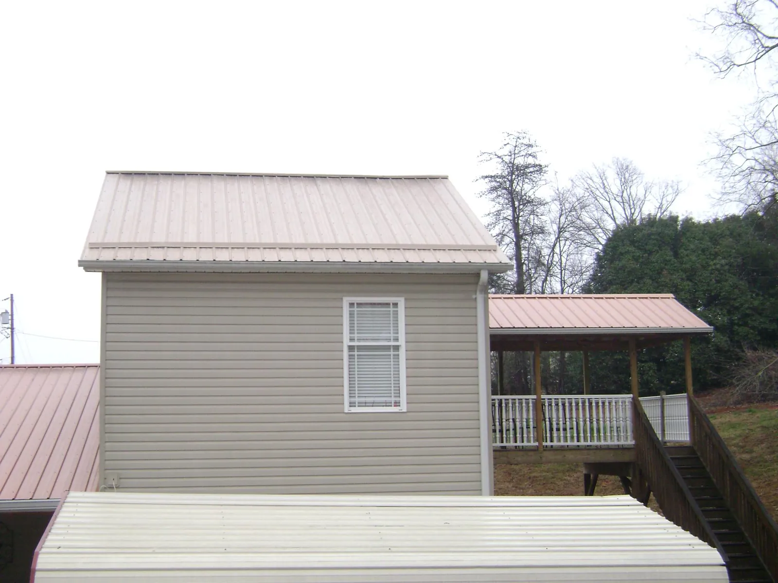 Tan metal roofs on a two story addition and attached porch, from a Roof Replacement job in Swarthmore