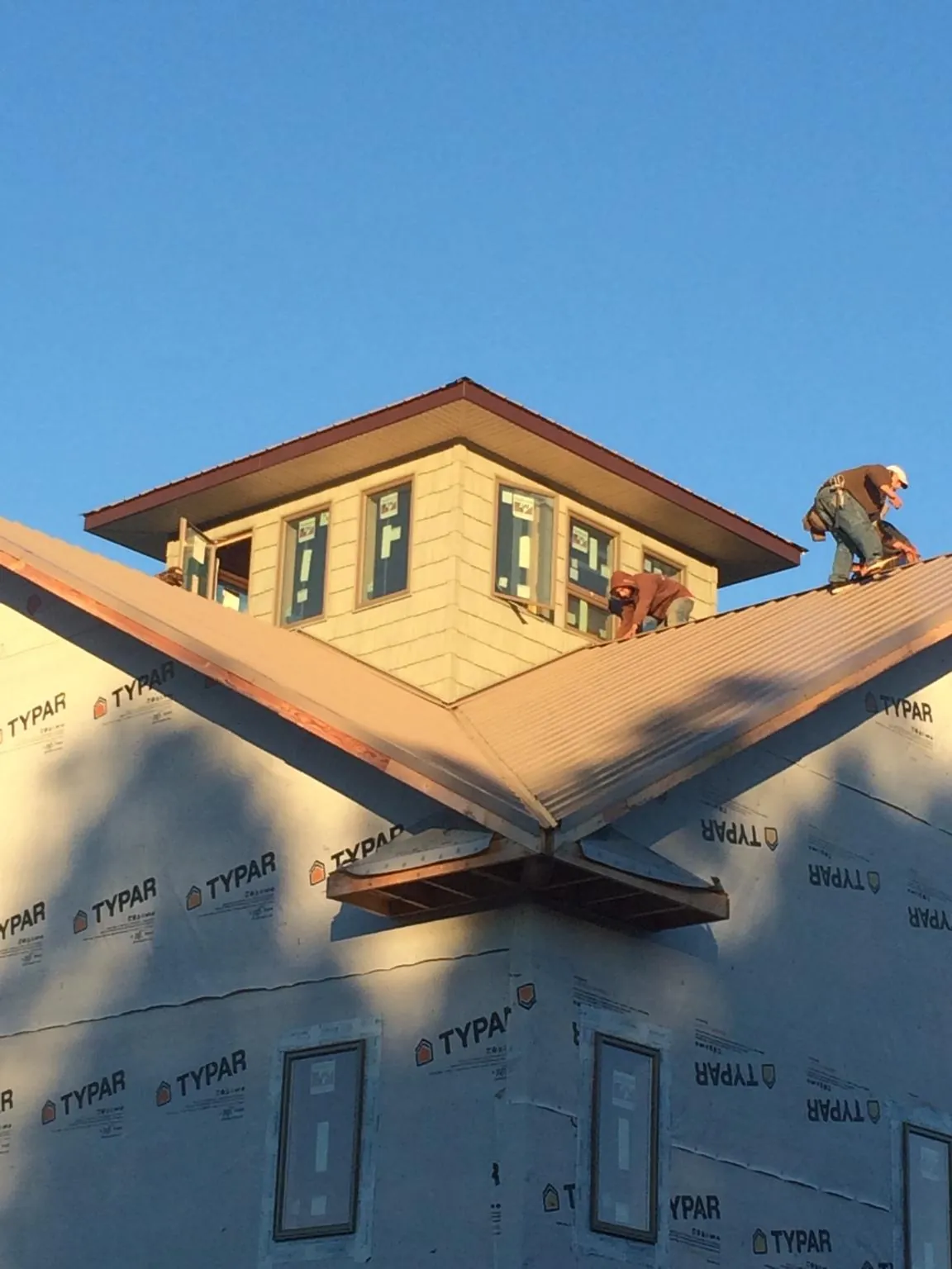 Roofers working around a rooftop cupola on a new metal roof at sunset — Roof Waterproofing in Swarthmore by Roofing Brothers